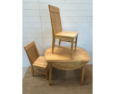 A light oak or pine drop sided table with two slat back chairs 
