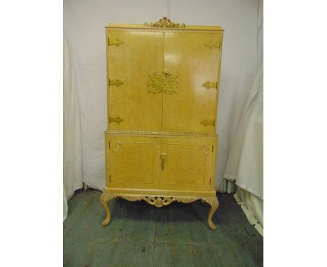 An Epstein rectangular light oak veneered cocktail cabinet, hinged doors on four scroll legs