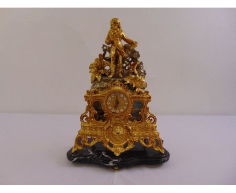 A French 19th century style gilt metal mantle clock surmounted by a figurine of a boy all on shaped marble base