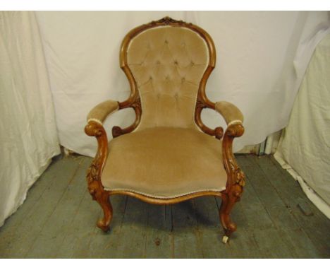 A Victorian upholstered mahogany button back armchair on cabriole legs with original castors