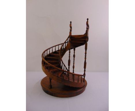 A mahogany display stand in the form of a spiral staircase with turned wooden columns and handrail on raised circular base, 6