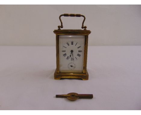A brass carriage clock of customary form, enamel dial, Roman numerals, to include key
