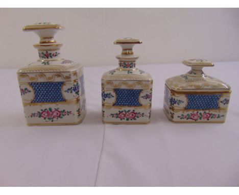 A set of three graduated ceramic perfume bottles, decorated with floral sprays and drop stoppers