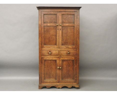 An early 19th century fruitwood cupboard, two panelled doors over two short drawers, with further cupboards beneath, standing
