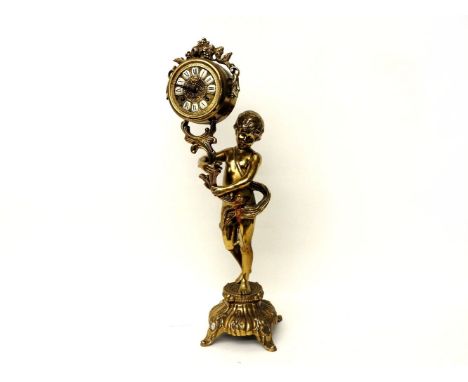 A brass mantel clock, the circular dial with Roman numerals on enamel, supported by a young boy on a rococo base