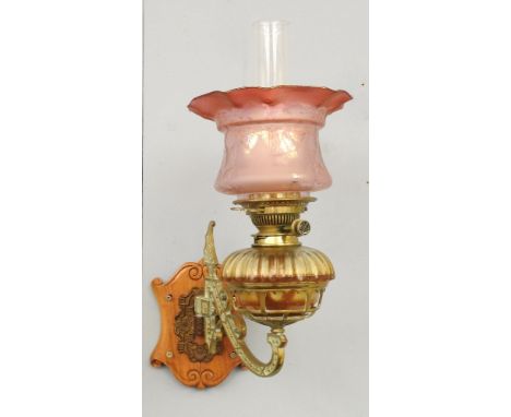 A brass mounted wall oil lamp, with etched cranberry glass shade
