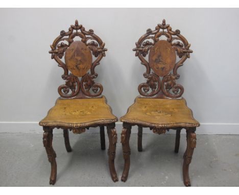 PAIR OF 19th CENTURY CONTINENTAL WALNUT HALL CHAIRS, overall inlaid with reserve panels of hunting figures and game within fo