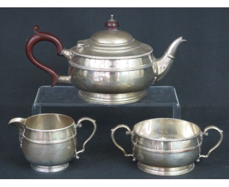 GEORGE V SILVER THREE PIECE BACHELOR'S TEA SET comprising teapot, cream jug and sucrier, having egg and dart border, scrolled