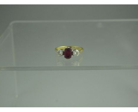 AN 18ct GOLD, DIAMOND AND RUBY THREE STONE RING.  The central oval cut ruby measures 7.5mm x 5.5mm, having a brilliant cut di