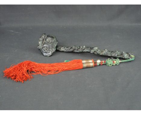 CHINESE CARVED GREEN/BLACK HARD STONE RUYI SCEPTRE overall decorated with foliate scroll work and having braided tassels.  13