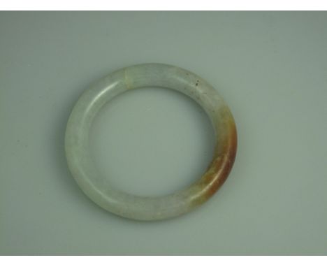 A POLISHED PALE GREEN AND BROWN JADE BANGLE.  Diameter 84mm, inner diameter 63mm. CONDITION REPORT: In good condition, no obv