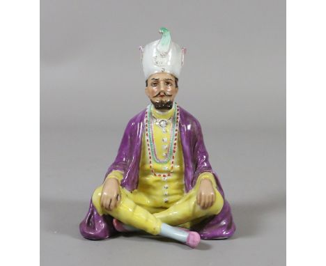 A William Goebel china figure. Coloured in enamels and modelled as a Middle Eastern Prince sat with crossed legs. Incised mar