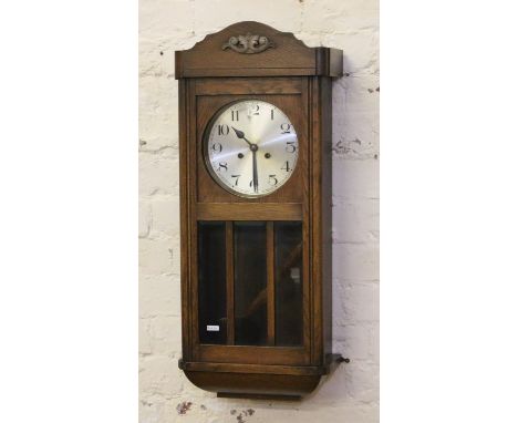 An oak cased eight day wall clock chiming on a gong.