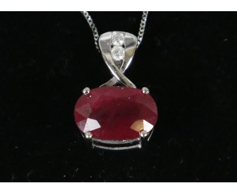 An 18 carat white gold pendant set with a large ovoid ruby and two diamonds supported on a 9 carat white gold necklace.