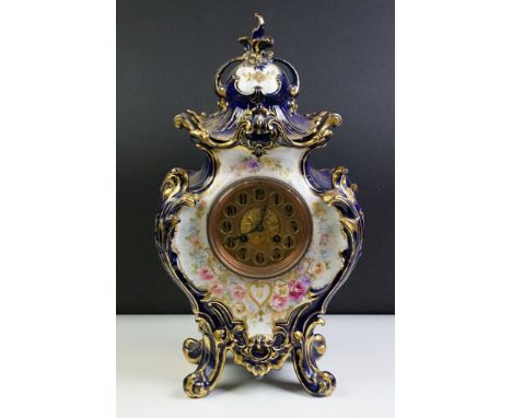 Ceramic mantle clock having moulded scrolled acanthus leaf detailing with floral detailing, and round face to front. Movement