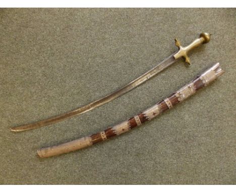 An antique Eastern brass-hilted curved sword in scabbard, the 28.5" blade with inscription, the scabbard with decorative silv