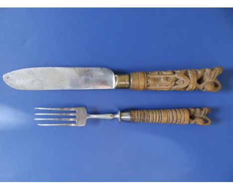 An early 20thC knife &amp; fork with carved wooden handles, each surmounted by a stylised lion, the fork dated 1905,  the kni
