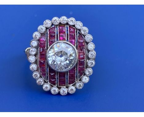 An Art Deco ruby &amp; diamond oval panel ring in platinum, the central millegrain set old cut diamond within rows of calibre