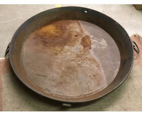 A rustic metal skillet type pan with four looped carrying handles, 103.5 cm diameter x 12 cm high