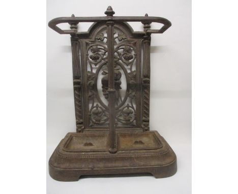 A late 19th century, cast iron stick stand with finials over a fruit, vine and floral panel, front pillar and twin drip trays