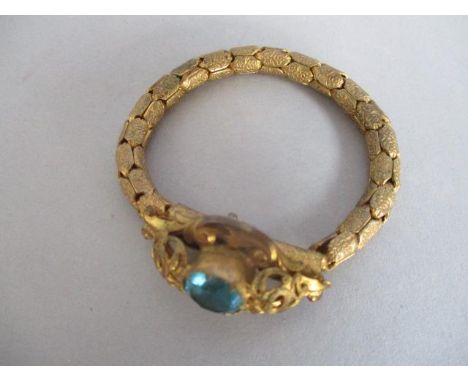 A gilt metal articulated bracelet fashioned as a cobra, the head seat with a blue cabochon 