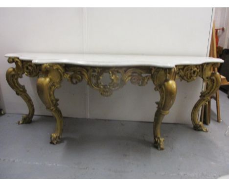 A Victorian carved gilt wood console table having triple serpentine fronted, marble top, over a scrolled leaf frieze, raised 