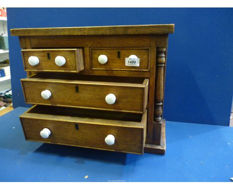 A small Oak miniature chest of drawers with two small over two long drawers having turned pillar decoration to front and smal