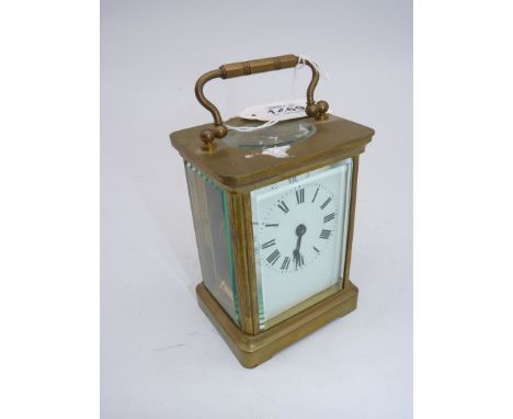 A brass cased bevelled glass Carriage Clock having an enamelled face with black Roman numerals and hands, the balance wheel v
