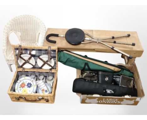 A small wooden bench together with a wicker camper, wicker chair, and a box containing folding easel, folding stool, camera t