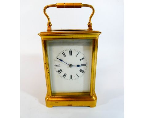 A brass carriage clock with striking movement, height with the handle up 19cm   Top oval glazing missing 