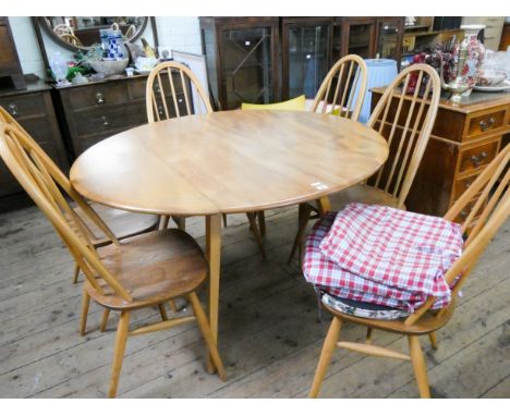 An oval Ercol light oak finished drop leaf dining table together with six matching stick back chairs  