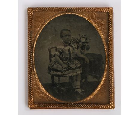 19th Century sixth plate ambrotype, of a boy seated in a dress by a bunch of flowers