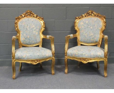 A pair of 20th century with heavily carved floral giltwood armchairs on cabriole legs, with floral upholstery, together with 