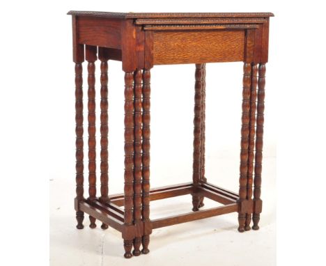 An Edwardian early 20th century oak nest of graduating tables having beaded decoration to the edge raised on turned bobbin le