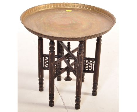 
A vintage 20th Century Indian / Middle Eastern brass topped Binares occasional table having engraved and repousse patterned 
