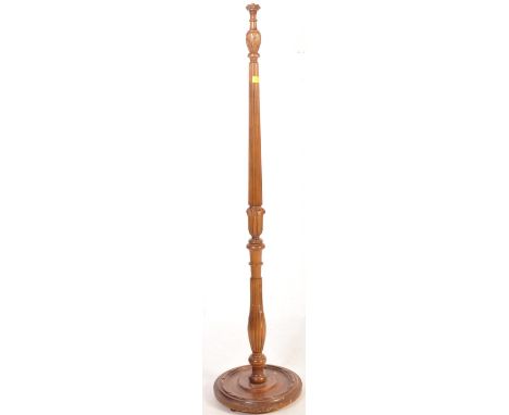 A 20th century solid mahogany standard floor lamp having a reeded tapering body carved details to the top and bottom on a cir