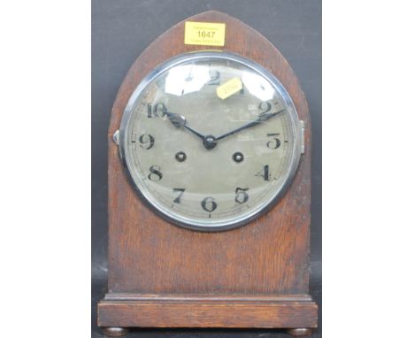 A nearly 20th century circa. 1930s oak mantle clock of domed form raised on a plinth base with silvered dial and black numera
