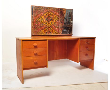 A mid-century teak wood dressing table by Stag Furniture. Raised on squared legs with raised pedestals of drawers having larg