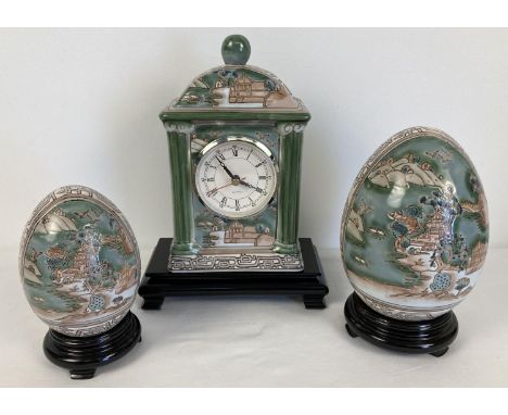 3 matching Chinese ceramic items on wooden stands. A quartz mantel clock and 2 ornamental eggs. Decorated in panelled design 
