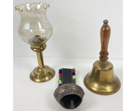 3 vintage items of metal ware. A wooden handled brass bell, a vintage cow bell and a brass candlestick holder with fluted edg