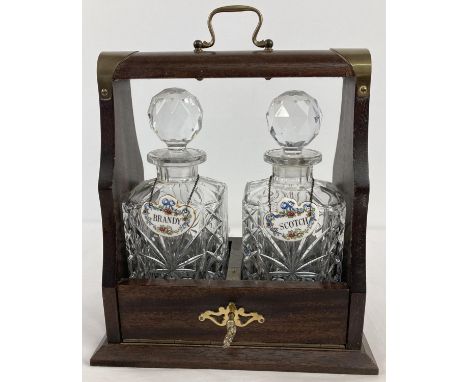 A vintage dark wood tantalus housing a pair of cut crystal square shaped decanters with ceramic decanter labels. Fine bone Ch