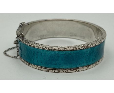 A modern silver and turquoise coloured guilloche bangle with push clasp and safety chain. Floral engraved detail to body and 