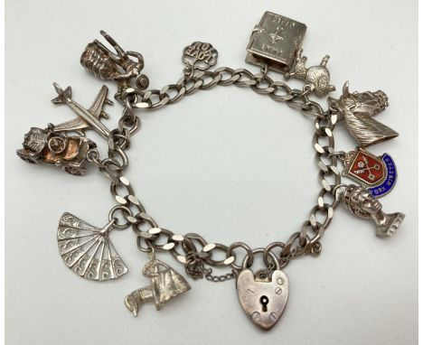 A vintage silver curb chain charm bracket with padlock clasp, safety chain and 11 silver charms. Charms include: opening bibl