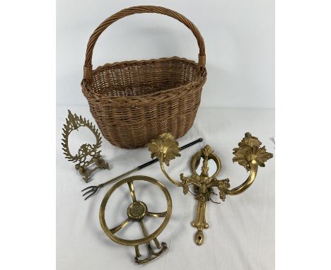 A vintage wicker shopping basket containing a small collection of brass ware items. To include a mirror backed wall light wit
