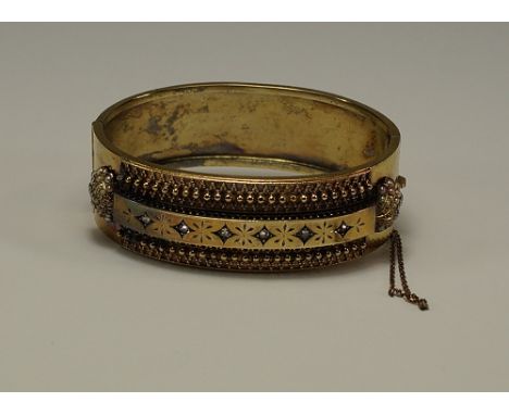 A Victorian yellow metal Etruscan revival bangle, the central bar with mine cut diamonds, flanked by beading and terminating 