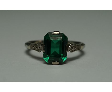 A 19k white gold and emerald cut green spinel dress ring, the outer shank cast with foliate design, approx size Q/R, approx 4