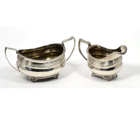 A George III silver cream jug and twin handled sugar basin, Thomas Barker, London 1818, oval with gadroon rim on bracket feet