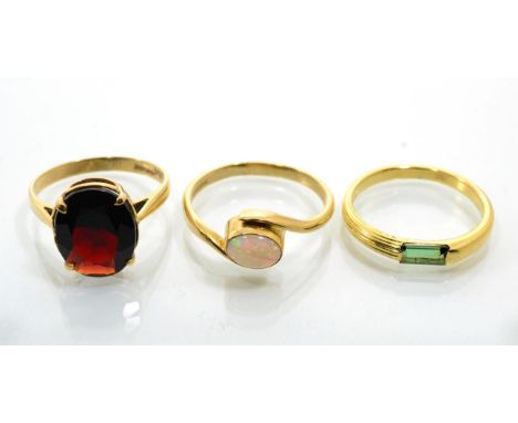 A 9 carat gold garnet ring, an oval cut garnet in a claw setting, to knife edge shoulders, finger size M; a 9 carat gold opal