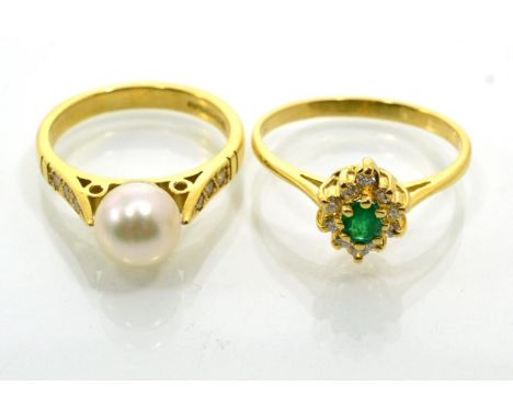 An emerald and diamond cluster ring, an oval cut emerald within a border round brilliant cut diamonds, to knife edge shoulder