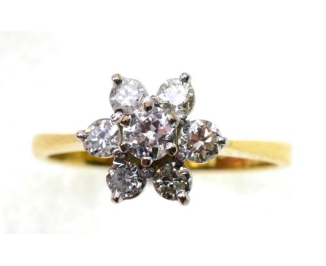 An 18 carat gold diamond cluster ring, an old cut diamond within a border of six round cut diamonds in claw settings, to knif